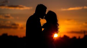 夕暮れ時や逆光で、ロマンチックにキスをしているカップルのシルエット。